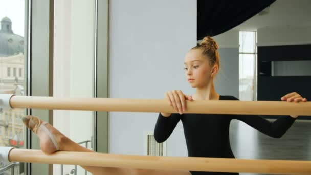 Retrato de bailarina jovem que se estende perto do ballet barre no estúdio . — Vídeo de Stock