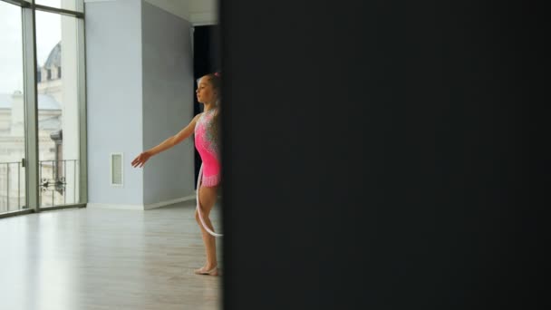 Jovem attcactive menina no corpo rosa treinando um exercício de ginástica com um aro no estúdio . — Vídeo de Stock