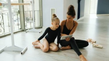 Sevimli genç kız ile bir şey tblet üzerinde stüdyoda dinlenirken izlerken öğretmeni.