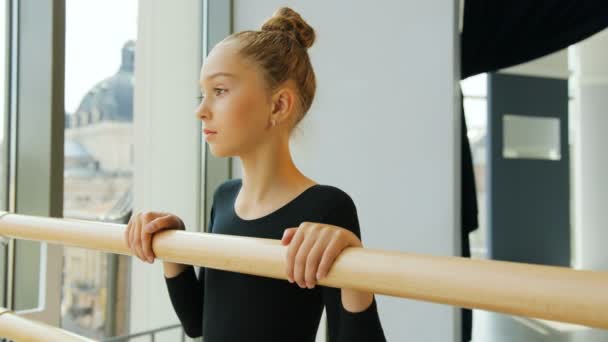 Portret młodej baletnicy, stojący w pobliżu balet barre w studio i uśmiecha się na aparat. — Wideo stockowe