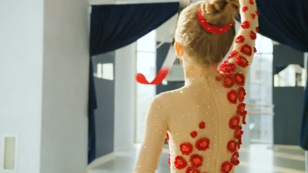 Portrait de petite gymnastique gracieuse tournant le ruban rouge dans le studio blanc . — Video