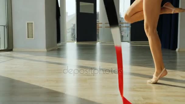 Close up shot of little gymnastics legs in red spinning the ribbon while doing the gymnastics exercise in the studio. — Stock Video