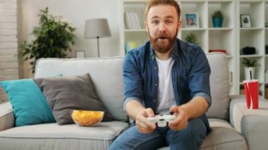 Xbox oyun oynayarak ve evde oturma odasında kanepede otururken kazanmak almak mutlu genç duygusal hipster.