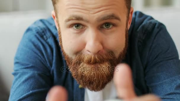 Retrato de joven hombre emocional con barba jugando juego en xbox mientras está sentado en el sofá en casa en la sala de estar. De cerca. . — Vídeos de Stock