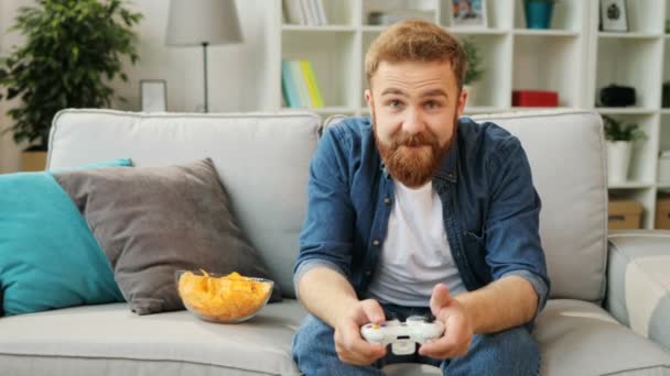 Homem emocional atraente feliz jogando jogo em casa na sala de estar, obtendo vitória e se sentindo tão feliz . — Vídeo de Stock