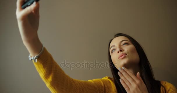 Portret van mooie lachende vrouw selfie binnen te nemen. Mooie jonge vrouw nemen van foto's van zichzelf thuis. Glimlachend en verzenden kussen voor de camera. — Stockvideo