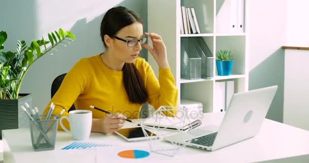 Hermosa mujer de negocios quitándose las gafas después del trabajo. Mujer joven relajándose después de terminar el trabajo en la oficina . — Vídeos de Stock