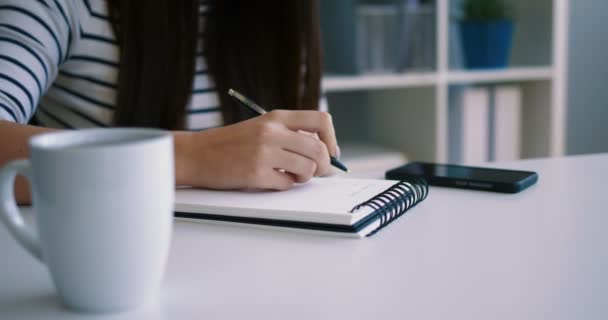Gros plan femme écrivant dans le bloc-notes, carnet au bureau. Femme mains notant des informations. Gros plan — Video