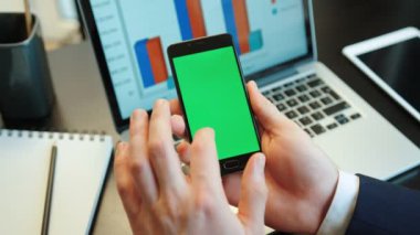 Akıllı telefon ile yeşil screan için analysising diyagramları kullanarak eller genç adam. Chroma anahtar. Dikey konumu.