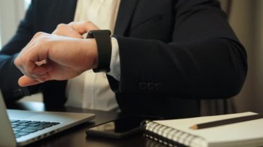 Dizüstü bilgisayar ve akıllı izle office arka plan üzerinde kullanarak takım elbise çalışkan genç iş adamı görüntüsünü kapatmak.
