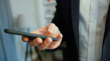 Takım elbise ve gömlek akıllı telefon kullanarak office arka plan üzerinde beyaz iş adamı elinde portresi.