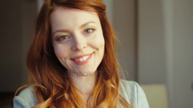 Kızıl saçlı ve kameraya bakarak ve gülümseyen mavi gözlü oldukça beyaz genç kadın portresi. Kapalı.