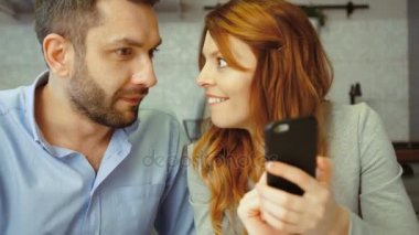 Genç çift akıllı telefon ev arka koltukta oturan fotoğrafları izlerken gülümsüyor. Kapalı.