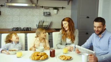 Beyaz genç aile mutfak. Babası okuma gazete, tanımlama bilgileri, dauther ve küçük oğlu gevreği süt ile yemek yeme anne.