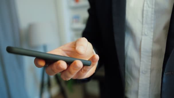 Porträt der Hände eines kaukasischen Geschäftsmannes in Anzug und Hemd mit Smartphone auf Bürohintergrund. — Stockvideo
