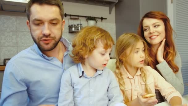 Portret rodziny jedząc śniadanie ojca za pomocą laptopa i dauther za pomocą tabletu na tle kuchnia. — Wideo stockowe