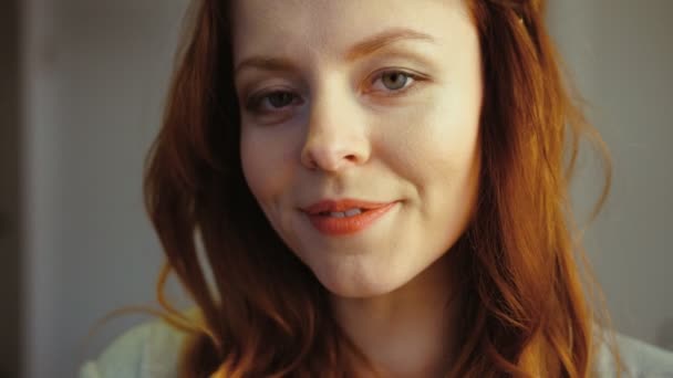 Kaukázusi gyönyörű fiatal nő, vörös hajú és kék szeme pózol a kamera, és mosolyogva fogakkal portréja. Beltéri. — Stock videók