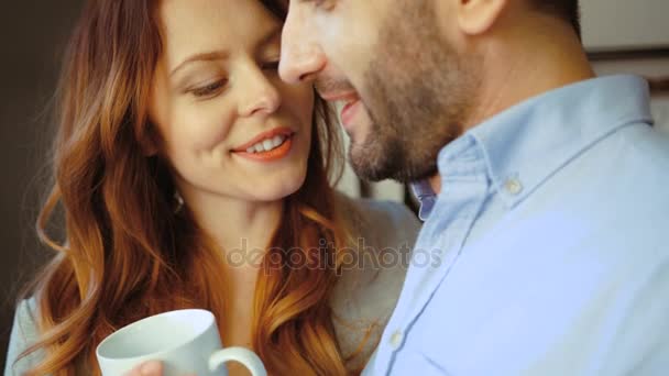 Retrato de casal encantador de jovem segurando xícara de café na mão e seu marido de pé na cozinha, sorrindo. Interior . — Vídeo de Stock