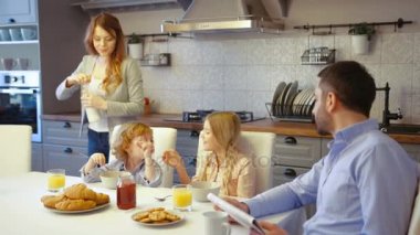 Beyaz genç aile mutfak. Çocuk pilakalar ve pul gazete okuyan babası ise beyaz çekici kadın dökülen süt.