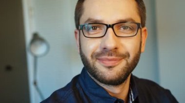 Gözlük kamera için poz ve ile gülümseyen sakallı genç beyaz güzel adam portresi. Kapalı.