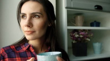 Sabah kahve içme ve rüya çekici beyaz kadın. Gülümseyen ve penceresine bakarak kadın. Yakın çekim. Kapalı