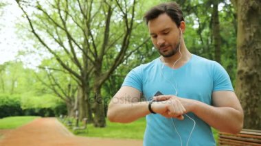 Çekici yakışıklı adam akıllı izlemek ve smartphone koşmak önce sabah parkta kullanarak uygun. Yakın çekim