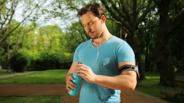 Çekici bir adam içme su jogging, koşu, sonra fitness eğitimi. Egzersiz yaptıktan sonra yenileniyor. Yakın çekim