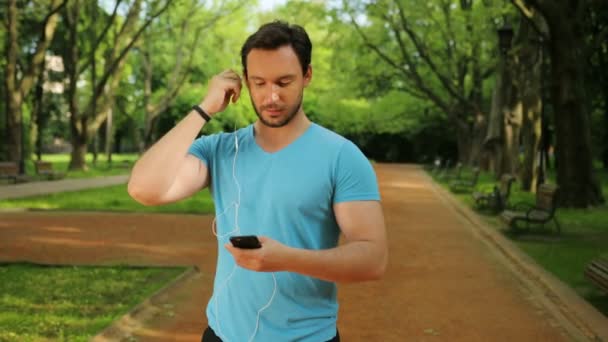 Μικρά ταιριάζει άνθρωπος ακούγοντας μουσική στα ακουστικά πριν από το τρέξιμο το πρωί, εκπαίδευση. Βάλτε σε ακουστικά. Κοντινό πλάνο — Αρχείο Βίντεο