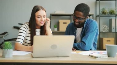 Afrika iş adamı ve birlikte ofiste çalışan, dizüstü bilgisayar ve bazı bilgileri yazma beyaz iş kadını. İş takım
