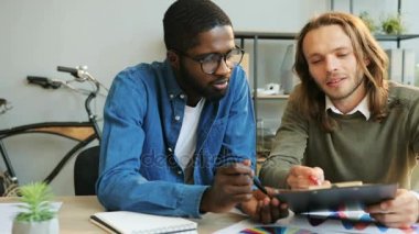 Ofiste çalışan Afrika ve beyaz iş adamı rapordaki bazı bilgiler analiz.