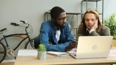 Modern ofis yeni Finans raporunda üzerinde çalışmak için dizüstü bilgisayar kullanarak Afrika ve beyaz iş erkek.