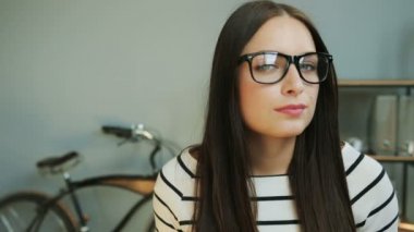 Portre fotoğraf makinesinin açılması gözlük içinde mutlu iş kadın kapatmak ve modern ofis arka planda gülümseyerek başlamak.
