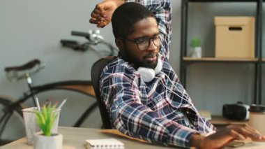 Modern ofis masasında dinlenirken sohbet için akıllı telefon kullanarak kulaklık ile Afrika genç iş adamı portresi.