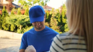 Exiciting genç kadın kurye karton kutu almak için özel belgelerin imzalanması.