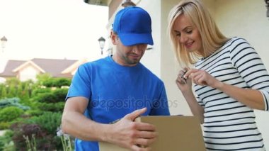 Çekici genç kadın kurye paketi almak için belgelerin imzalanması.