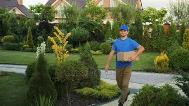 Evinde adında paket için mutlu bir kadın için karton ile yürüyüş kurye.