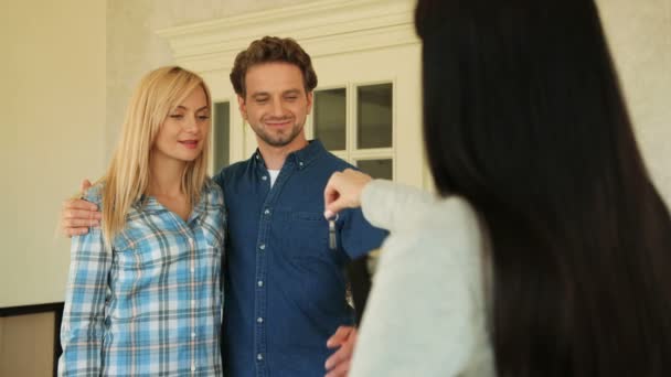Primer plano de la pareja ayand consiguiendo una llave de su nueva casa de su agente inmobiliario en la puerta de fondo de la nueva casa . — Vídeo de stock