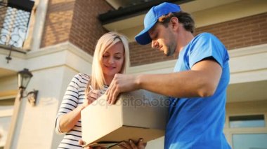 Çekici genç kadın kurye paketi almak için belgelerin imzalanması. Alttan görüntülemek.