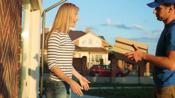 Attraktive junge Frau unterschreibt die Dokumente für die Paketannahme vom Kurier auf dem Garten Hintergrund. Seitenansicht. — Stockvideo