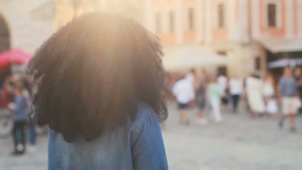 Close up retrato de cabelo encaracolado beatiful mulher africana andando na rua, girando e sorrindo na câmera no fundo da cidade velha com sol . — Vídeo de Stock