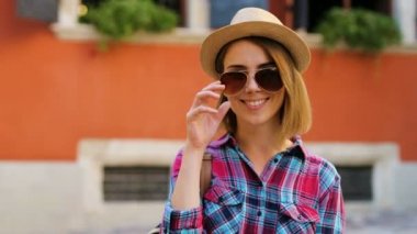 Kameraya poz ve şehir sokak arka planda gülümseyen güzel genç kadın. Yakın çekim.