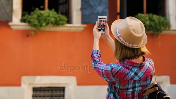 旧市街でスマート フォンを用いた美しい建物の写真を作る若いスタイリッシュな女性。背面から見る. — ストック動画