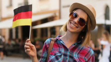 Kameraya poz ve şehir sokak arka plan üzerinde gülümseyen Almanya bayrağı mutlu çekici kadın. yakın çekim