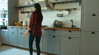 Modern mutfağında dans genç çekici kadın portresi. Yürüyüş ve dans kadın.