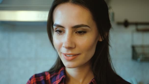 Close-up van portret van mooie, aantrekkelijke vrouw kijken naar de camera in haar keuken thuis. — Stockvideo