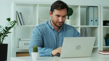 Şık modern tasarımı ile office içinde belgili tanımlık laptop üzerinde çalışıyor ve duygu tarafından bitirme çalışma gün mutlu çekici genç adam.
