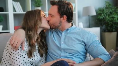 Genç çift birbirine bakarak ve dinlenirken öpüşme aşk iyon kanepe oturma odasında.