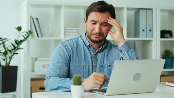 El hombre de negocios recibe muy malas noticias del informe en el portátil y se ve tan triste. Antecedentes . — Vídeo de stock