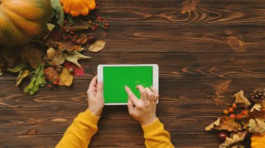 Üstten Görünüm. Sonbahar kompozisyon ile akçaağaç yaprakları, kabak ve beyaz tablet cihaz ile kahverengi ahşap masa üzerinde Yeşil perde. Chroma anahtar.