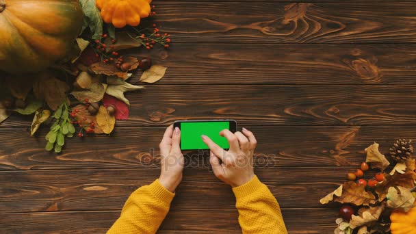 Gyönyörű őszi felülnézet juharfa zöld és tök a fából készült asztal. Nő, görgetés, nagyítás és megérinti okostelefonok touchsreen. Zöld képernyő. Chroma-kulcs. Vízszintes — Stock videók